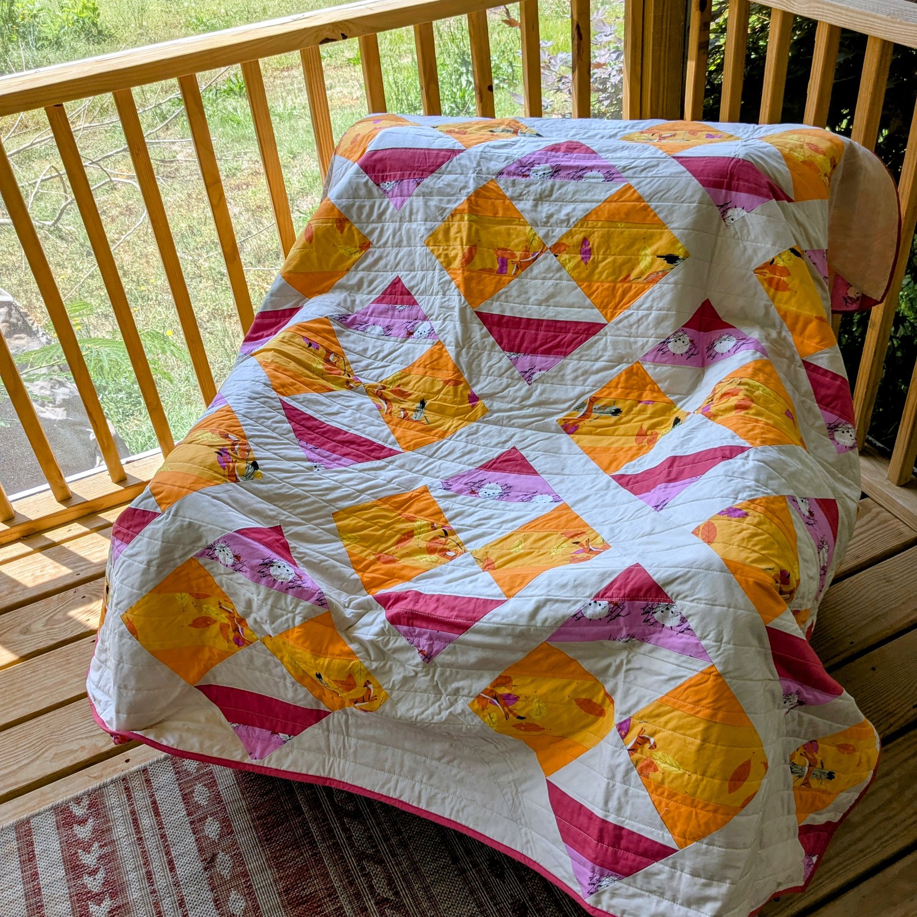 Citrus Star Quilt - Orange, yellow, and pink half-square triangle quilt with cat prints