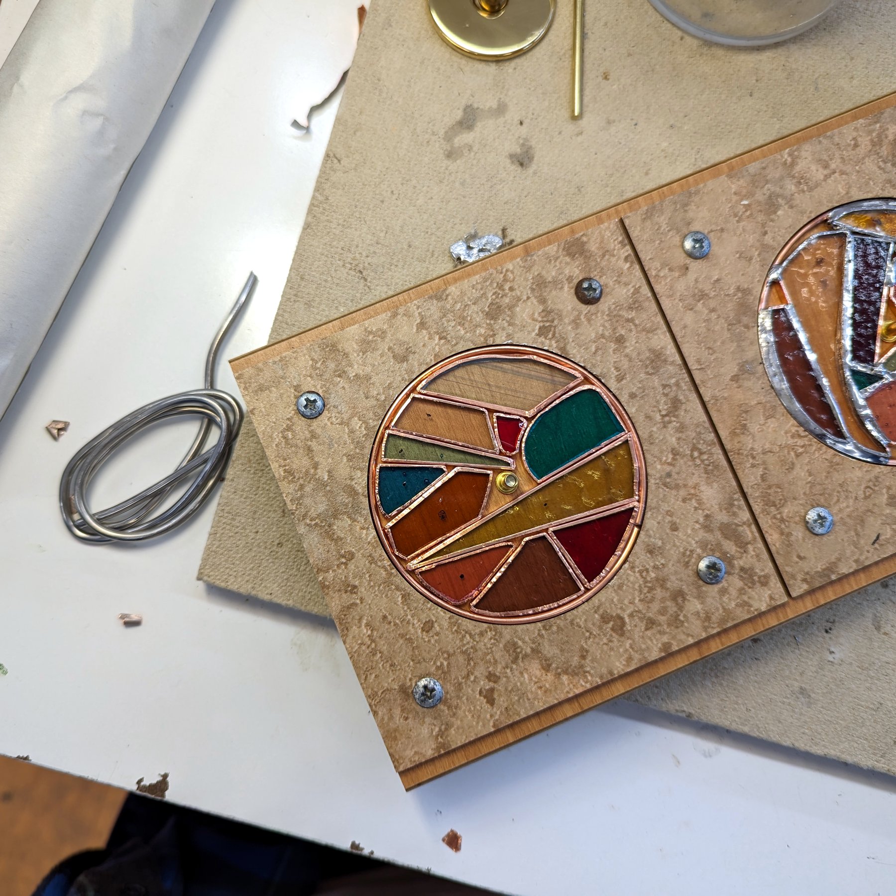 Two Kaleidoscope Discs - Pair of copper-framed round discs on a workbench